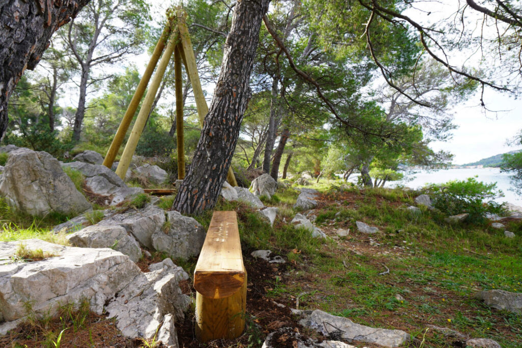 Drvena klupa s urezanim hashtag oznakama uz Spomenik volontiranju